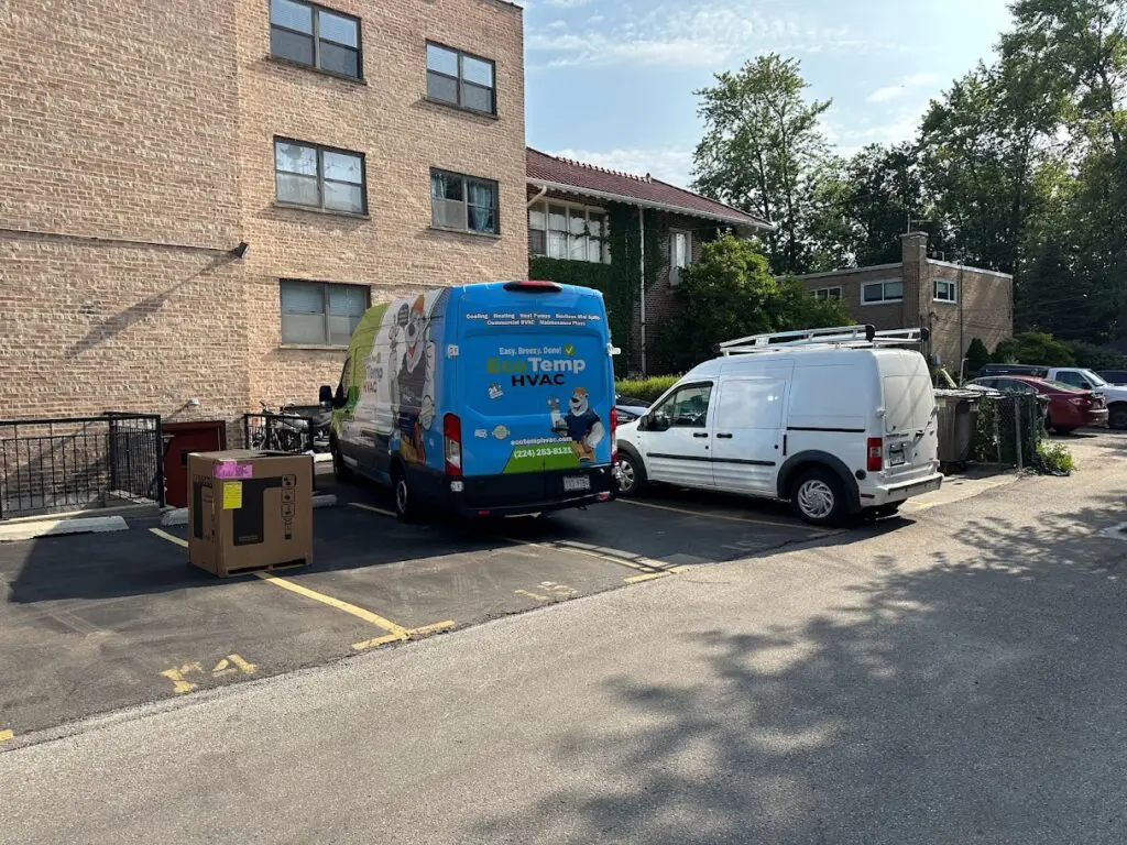A box with an air conditioner on the floor next to two vans outside of an apartment complex in Burbank IL.