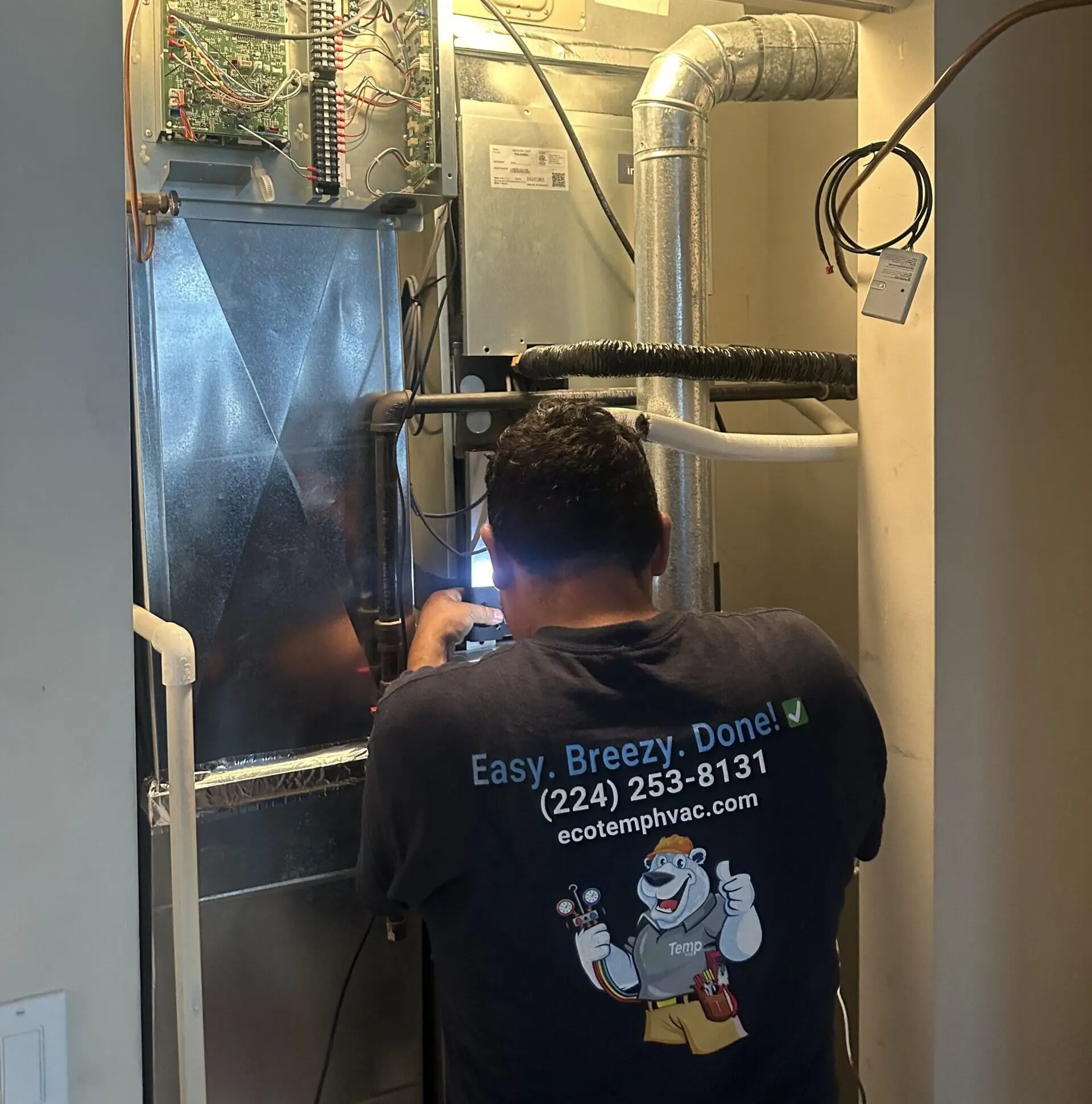 An HVAC technician from Eco Temp HVAC performing repair on a heating system in a residential property in Palos Park, IL.