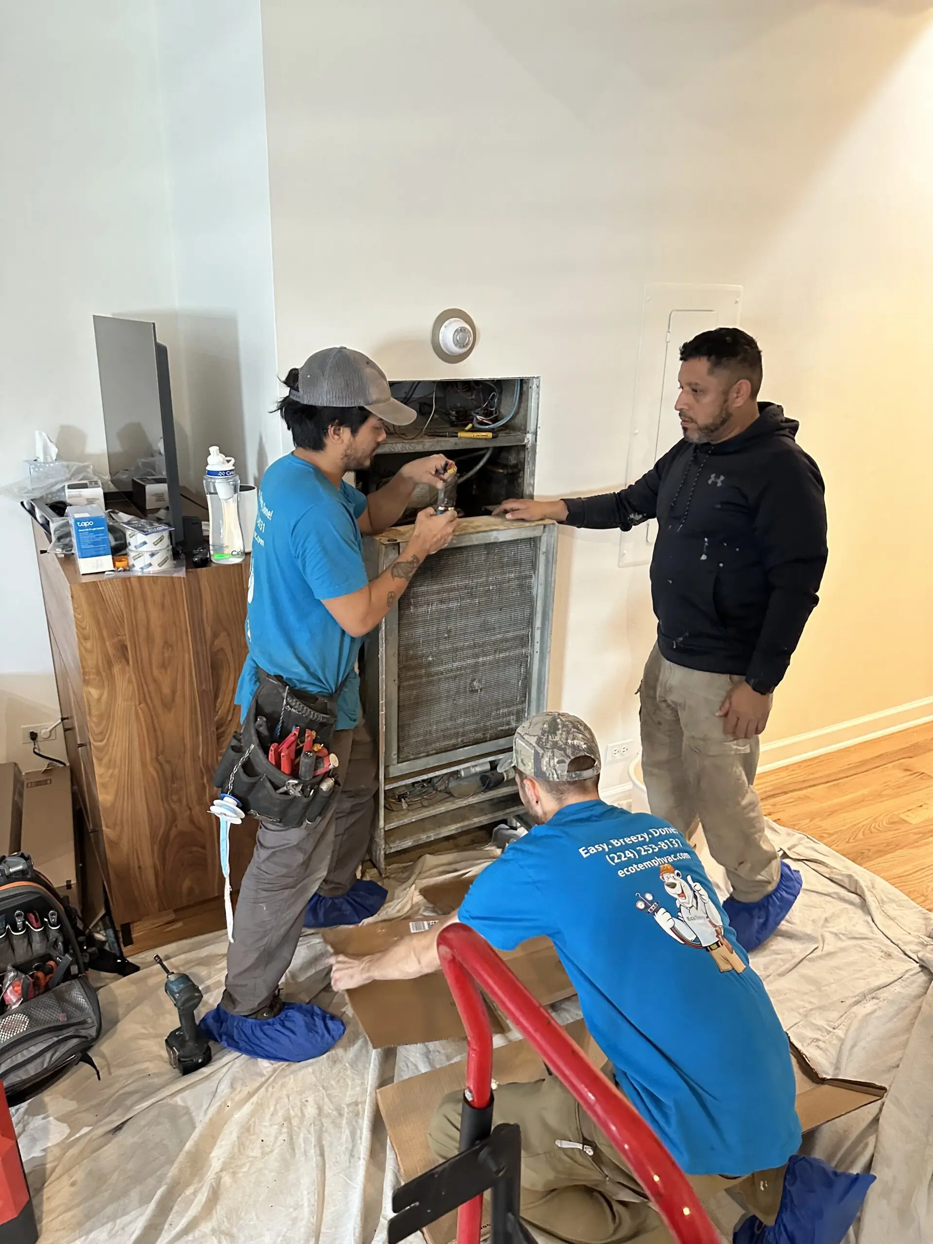 Eco Temp HVAC technicians repairing a furnace in a home in Aurora, IL, showcasing expertise and teamwork during a residential heating system service.