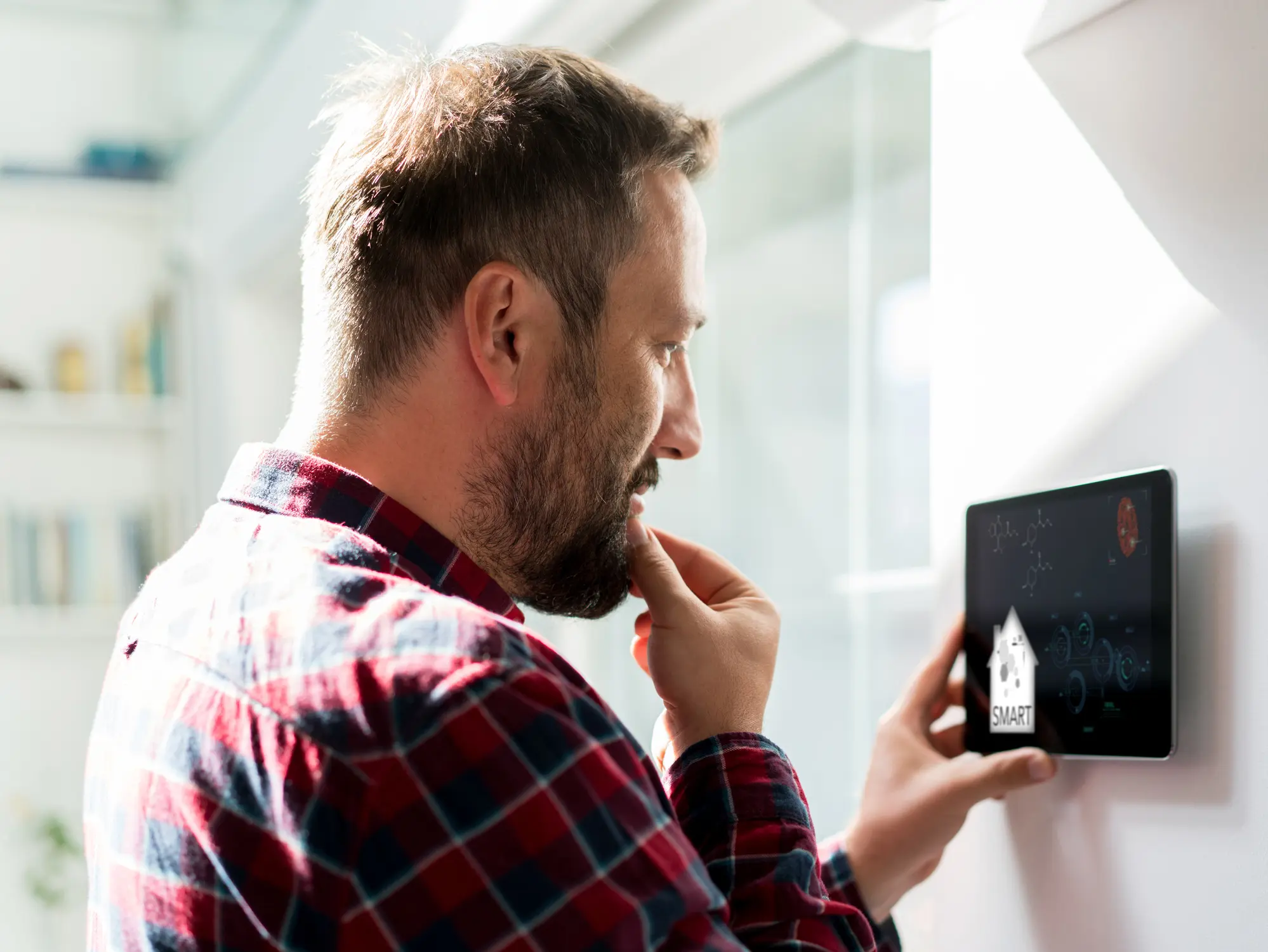 Man using smart thermostat inside of his home.
